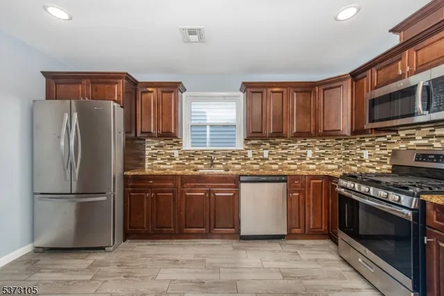 a kitchen with stainless steel appliances granite countertop a refrigerator stove a sink and a microwave