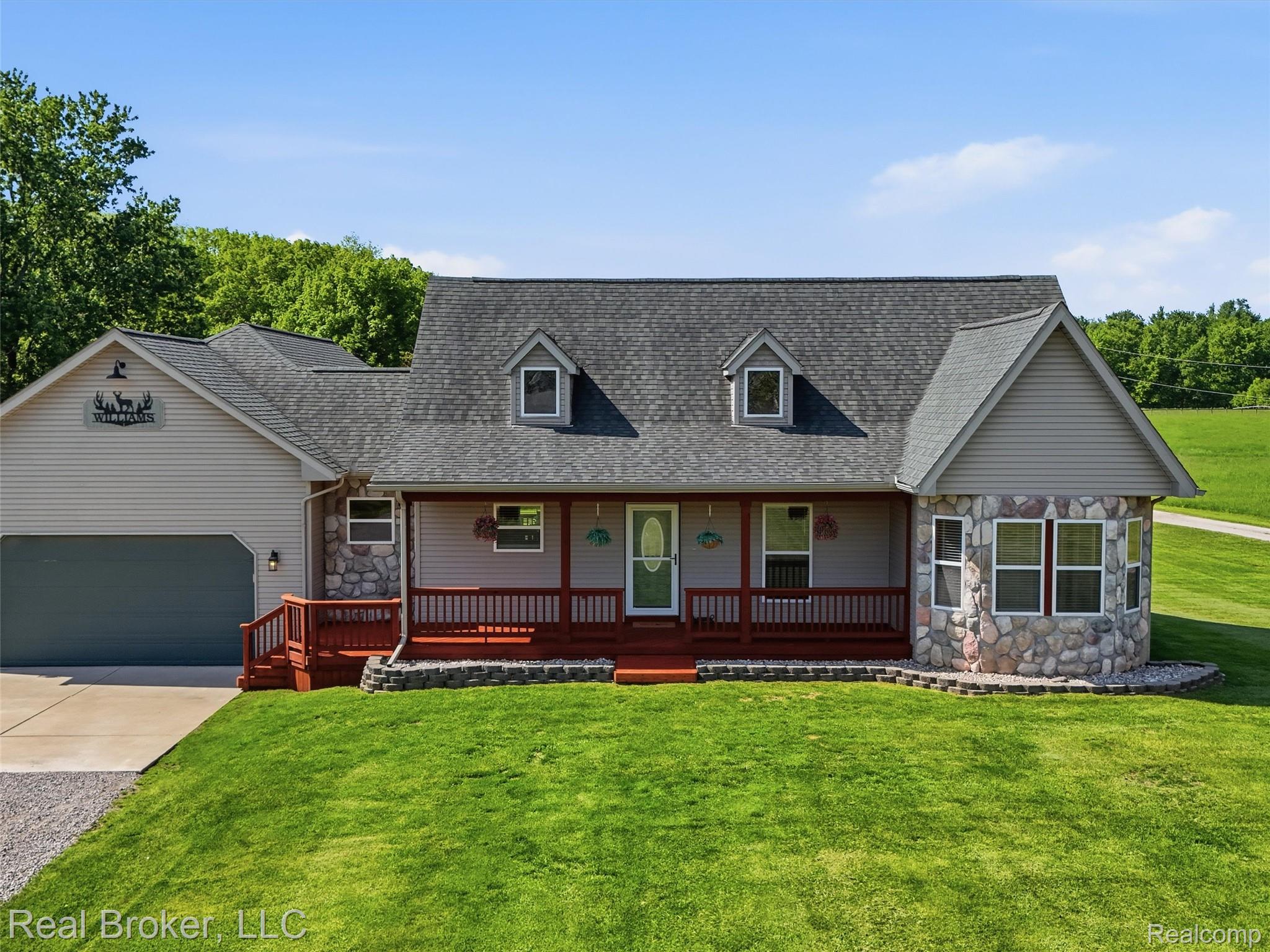 7271 West Ray Road Gaines, MI 48436 - Photo 2 of 48 Split-level home featuring a stone facade accent, covered front porch with a red-stained deck, dormer windows, and attached garage