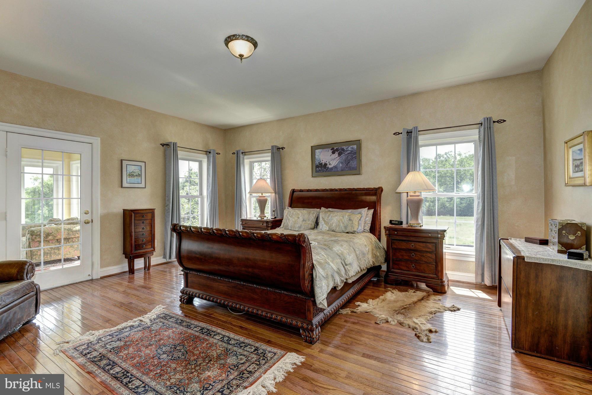 20500 Westerly Road Poolesville, MD 20837 - Photo 21 of 30 a bedroom with a bed a dresser and wooden floor