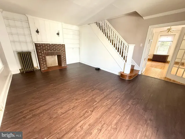 a view of an empty room with wooden floor and a fireplace