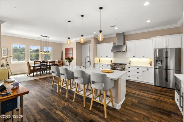 a large kitchen with a table chairs refrigerator and a wooden floor