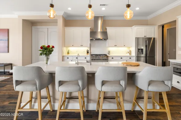 a kitchen with stainless steel appliances a dining table chairs and a refrigerator