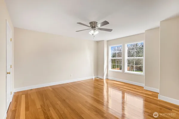 a view of empty room with wooden floor and fan