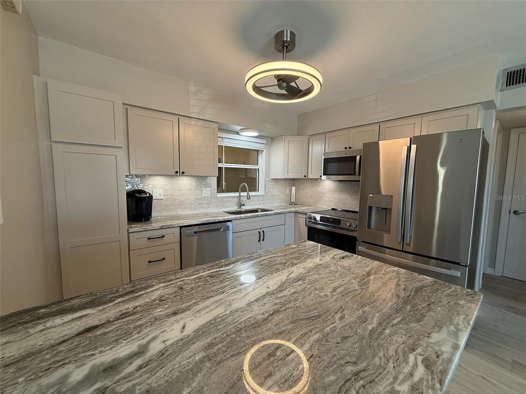 175 55th Avenue, Unit 109 St. Pete Beach, FL 33706 - Photo 11 of 27 a kitchen with a refrigerator a microwave and cabinets