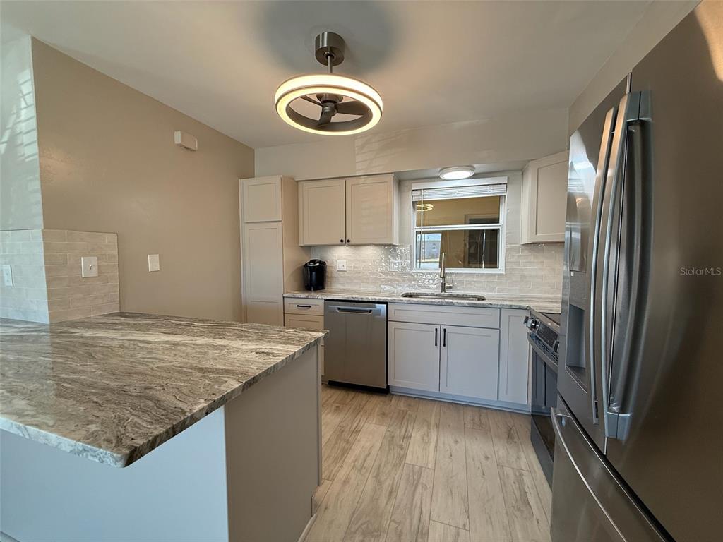 175 55th Avenue, Unit 109 St. Pete Beach, FL 33706 - Photo 12 of 27 a kitchen with a sink refrigerator and microwave
