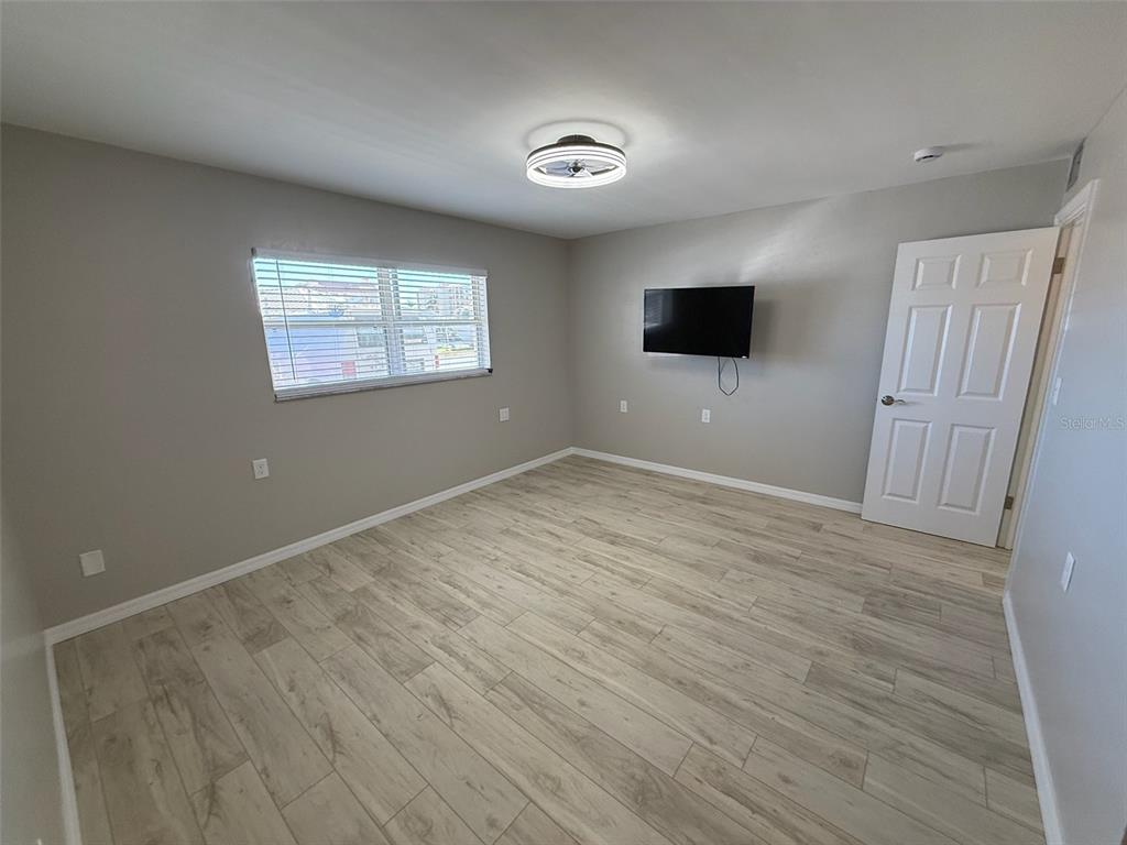 175 55th Avenue, Unit 109 St. Pete Beach, FL 33706 - Photo 15 of 27 an empty room with wooden floor and windows