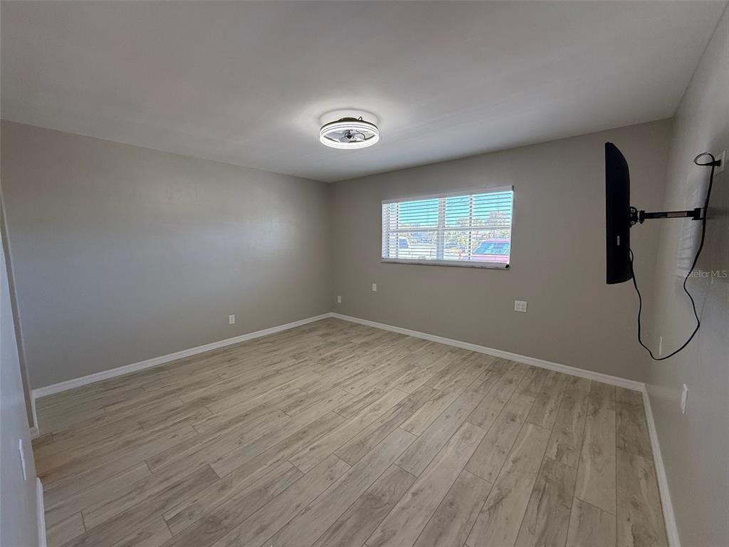 175 55th Avenue, Unit 109 St. Pete Beach, FL 33706 - Photo 16 of 27 an empty room with wooden floor and windows