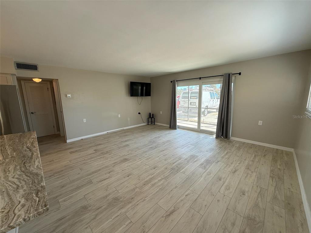 175 55th Avenue, Unit 109 St. Pete Beach, FL 33706 - Photo 3 of 27 an empty room with wooden floor and windows