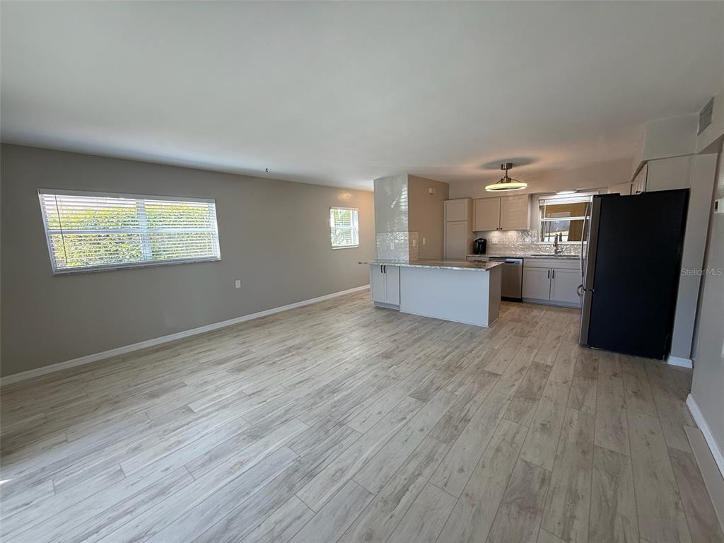175 55th Avenue, Unit 109 St. Pete Beach, FL 33706 - Photo 6 of 27 an empty room with wooden floor and windows