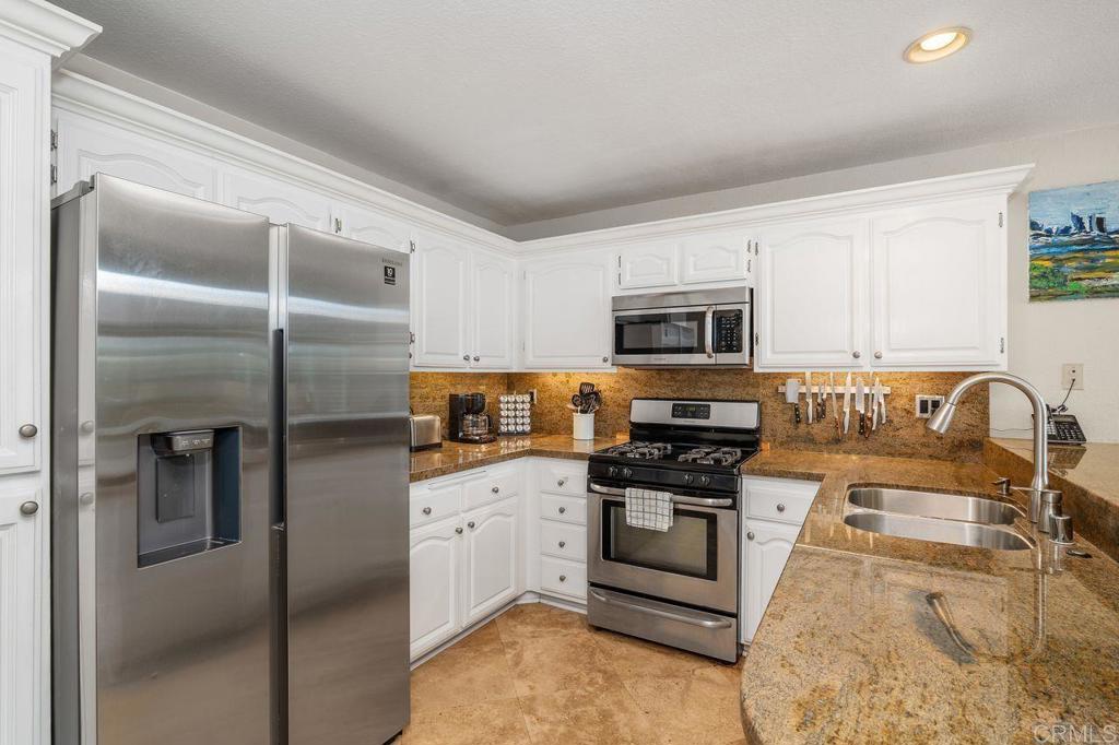 7010 Lantana Terrace Carlsbad, CA 92011 - Photo 13 of 45 a kitchen with stainless steel appliances granite countertop a refrigerator a stove top oven a sink and dishwasher