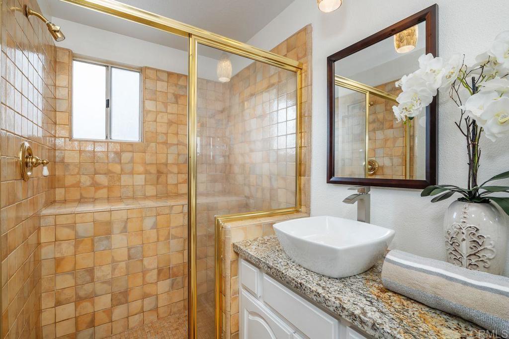 7010 Lantana Terrace Carlsbad, CA 92011 - Photo 27 of 45 a bathroom with a granite countertop sink a mirror and a shower