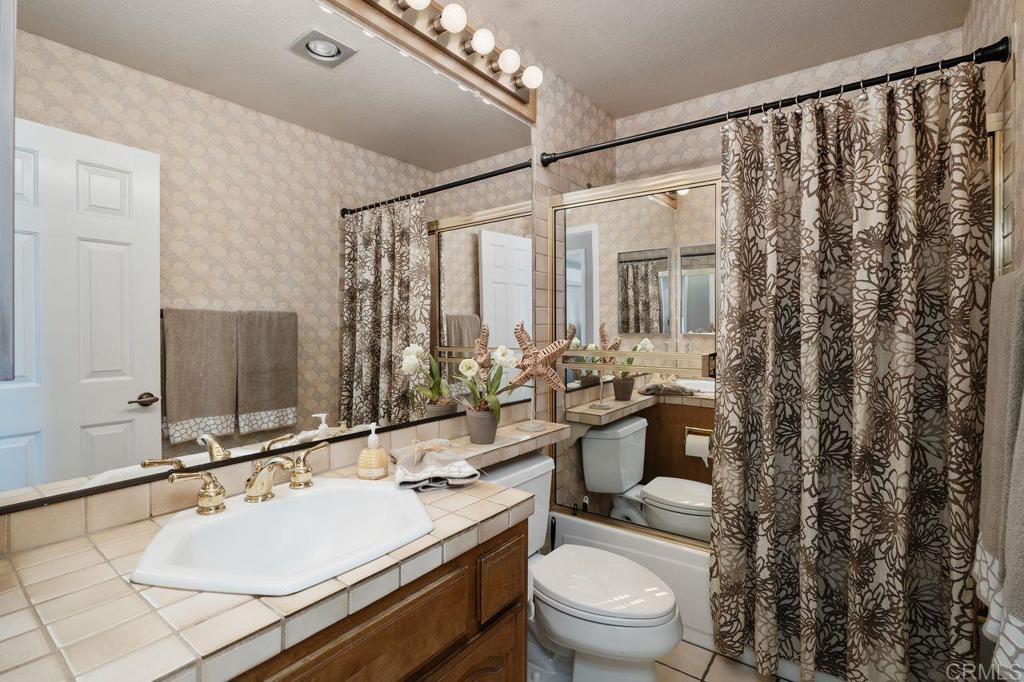 7010 Lantana Terrace Carlsbad, CA 92011 - Photo 32 of 45 a bathroom with a granite countertop sink a toilet a mirror and shower