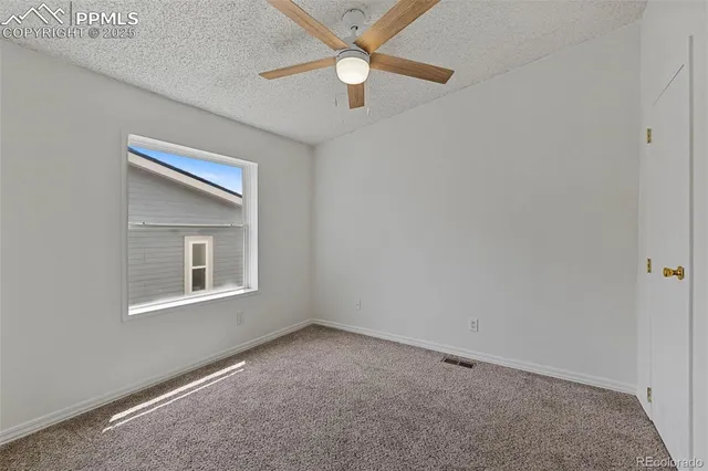 an empty room with a window and a fan