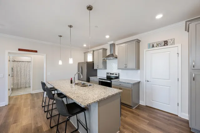 a kitchen with kitchen island a refrigerator a stove a sink a center island and a wooden floor