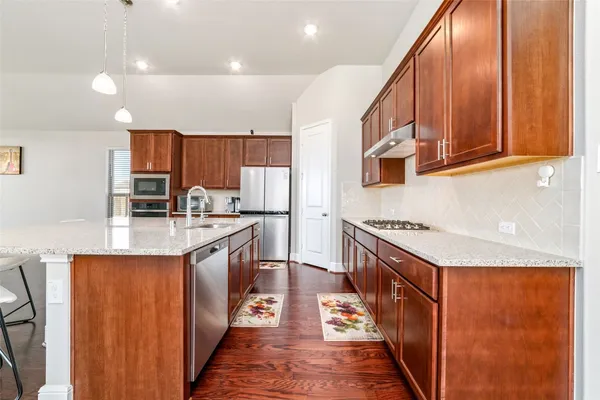 a kitchen with stainless steel appliances granite countertop wooden cabinets a sink and a stove