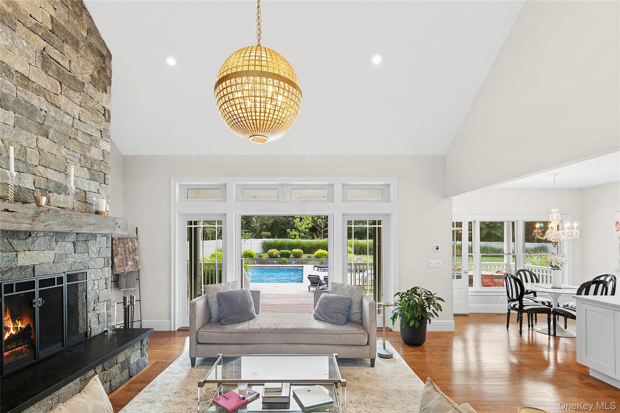 3470 North Bayview Road Southold, NY 11971 - Photo 4 of 25 Living room featuring a chandelier, light wood-style flooring, high vaulted ceiling, a fireplace, and recessed lighting
