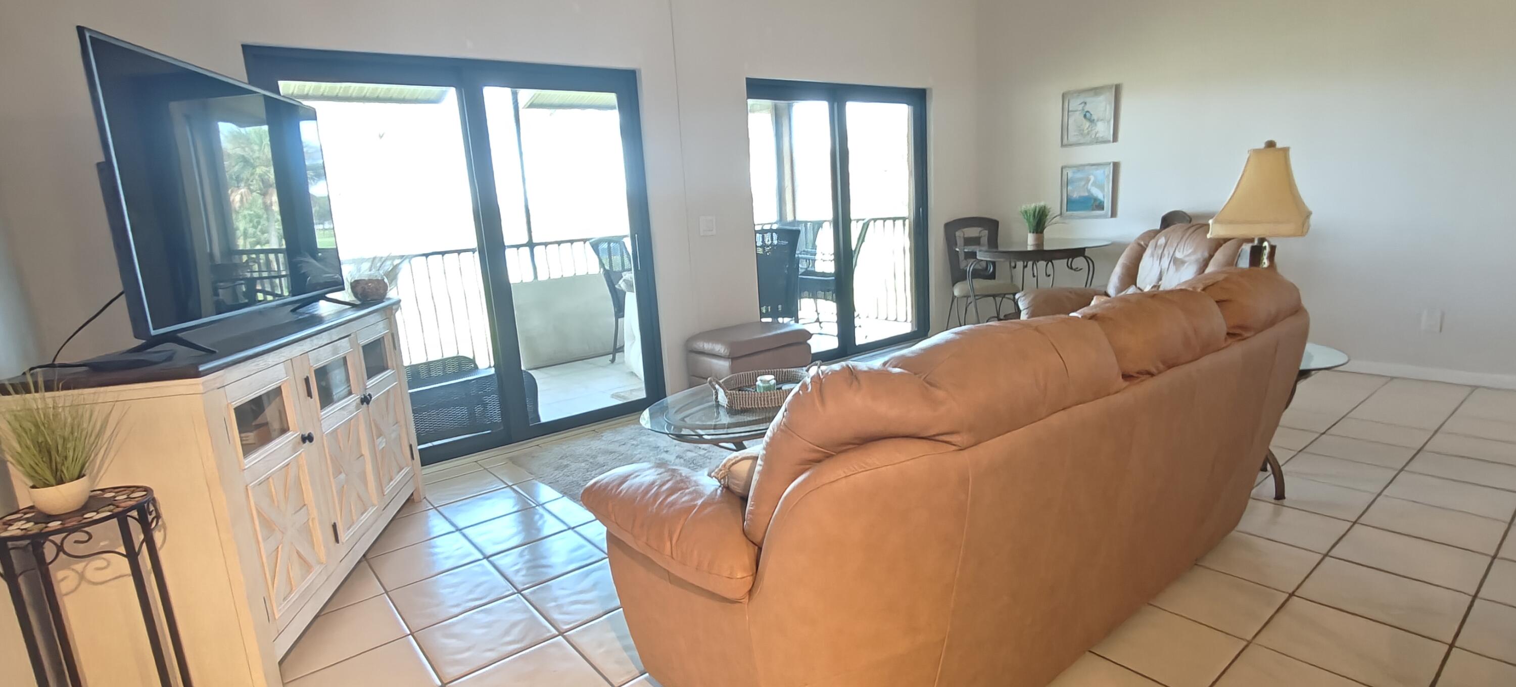 233 Northeast Edgewater Drive, Unit 203 Stuart, FL 34996 - Photo 14 of 30 a living room with furniture and a floor to ceiling window