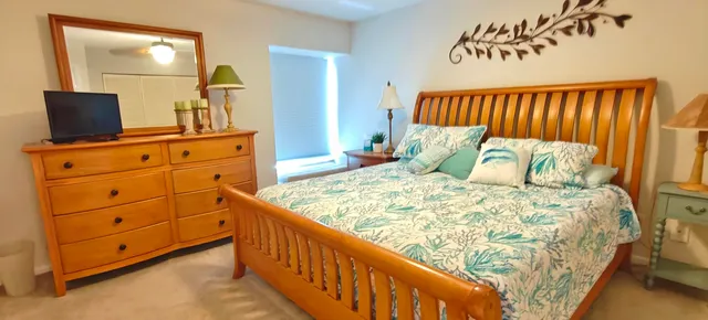 a bedroom with a bed and a flat tv screen on dresser