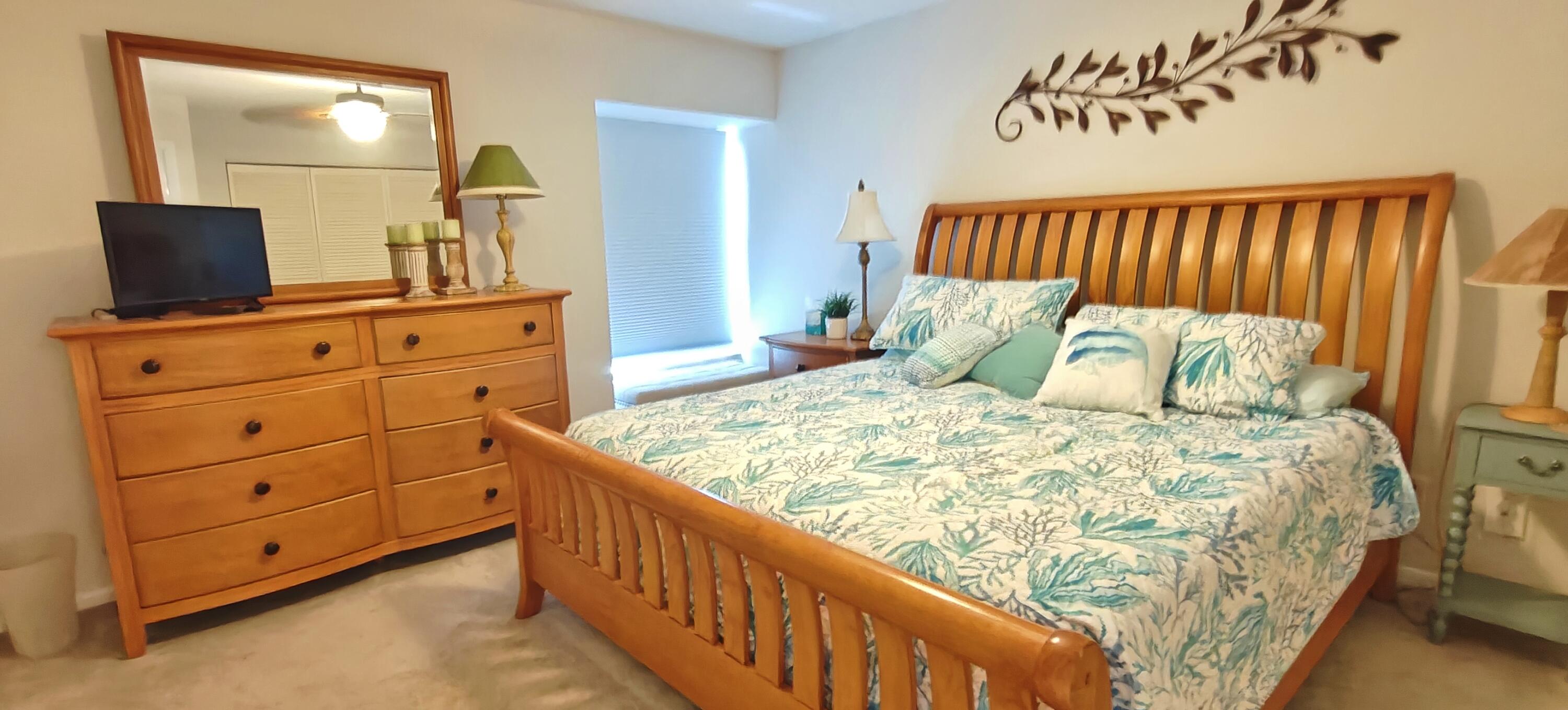 233 Northeast Edgewater Drive, Unit 203 Stuart, FL 34996 - Photo 15 of 30 a bedroom with a bed and a flat tv screen on dresser