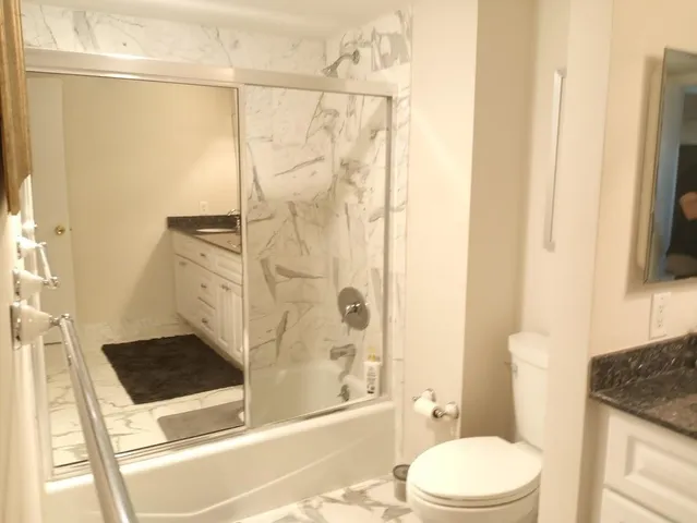 a bathroom with a granite countertop sink toilet and shower