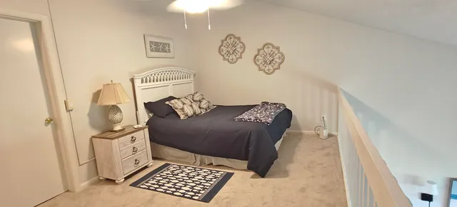 a view of a hallway to a bedroom with wooden floor and a bookshelf