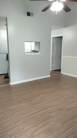 a view of an empty room with wooden floor and a window
