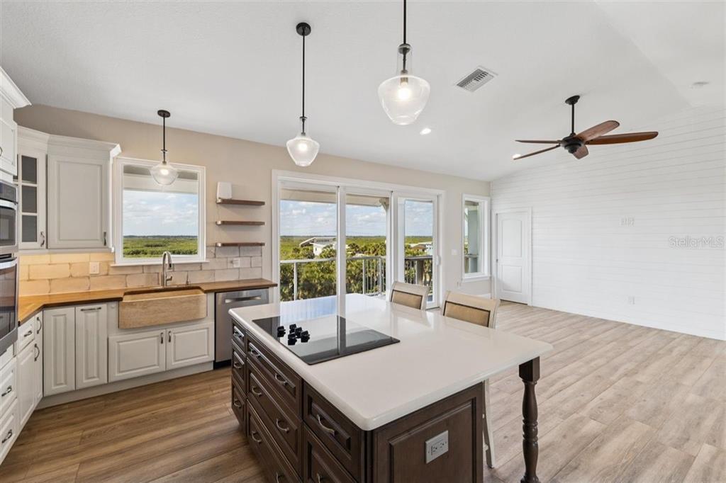 6191 Turtlemound Road New Smyrna Beach, FL 32169 - Photo 14 of 90 a kitchen with a stove a sink dishwasher a kitchen island with wooden cabinets and floor