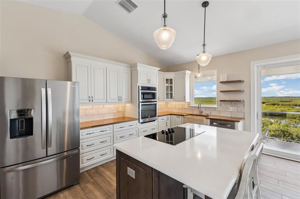 6191 Turtlemound Road New Smyrna Beach, FL 32169 - Photo 15 of 90 a kitchen with stainless steel appliances granite countertop a sink a stove a refrigerator a center island a stove and a center island