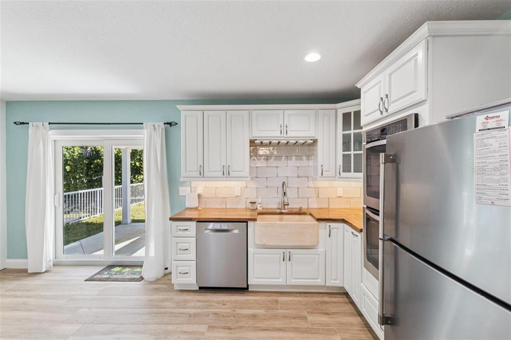 6191 Turtlemound Road New Smyrna Beach, FL 32169 - Photo 34 of 90 a kitchen with stainless steel appliances a refrigerator a sink cabinets and wooden floor