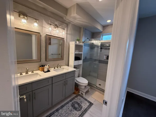 a bathroom with a double vanity sink toilet and shower