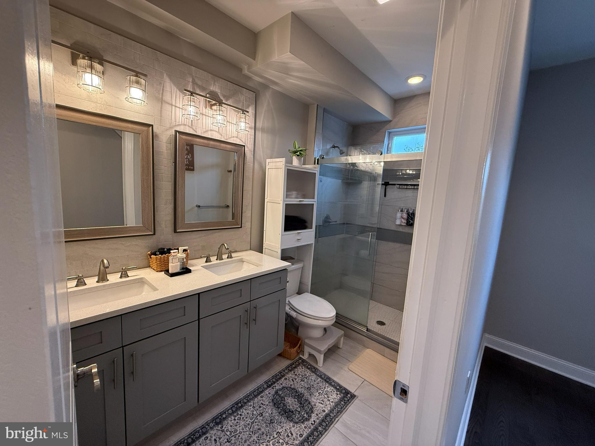 a bathroom with a double vanity sink toilet and shower