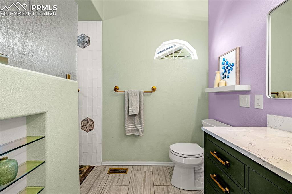 1310 Bison Ridge Drive Colorado Springs, CO 80919 - Photo 20 of 45 a bathroom with a granite countertop toilet a sink and a mirror