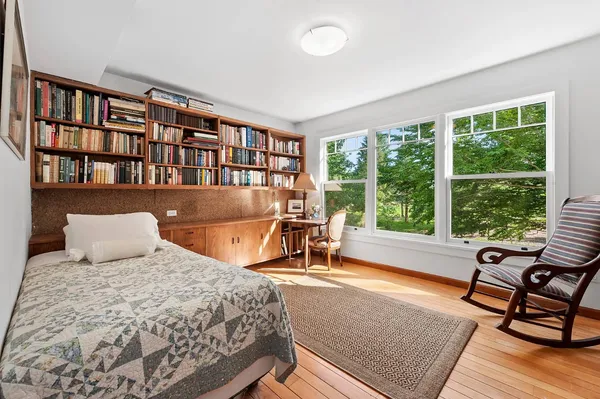 a bedroom with a bed a large window and a book shelf