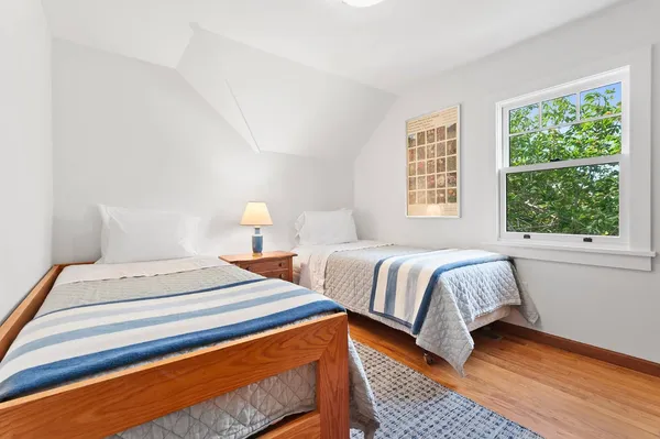 a bedroom with two beds and wooden floor