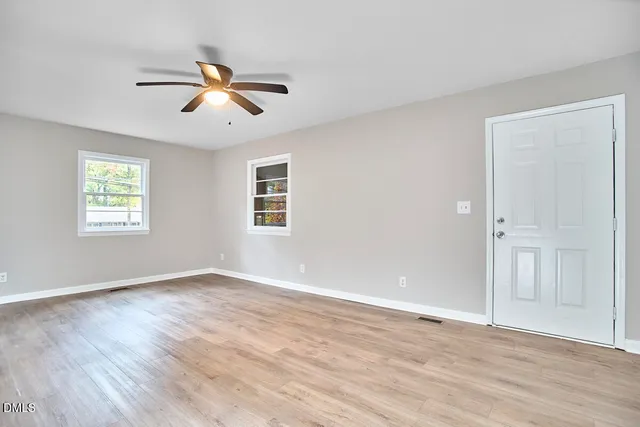 a view of empty room with wooden floor and fan