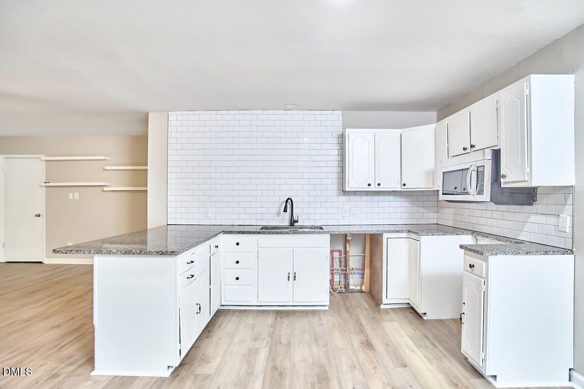 2128 Strebor Street Durham, NC 27705 - Photo 14 of 51 a kitchen with granite countertop a sink a stove and cabinets