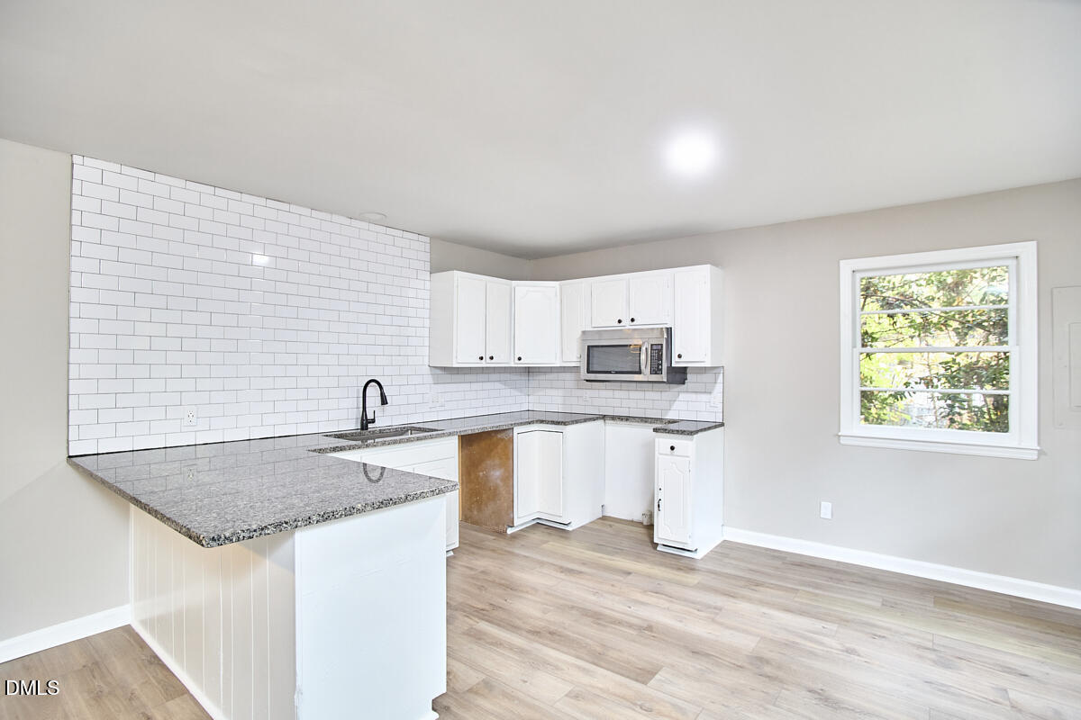 2128 Strebor Street Durham, NC 27705 - Photo 15 of 51 a kitchen with stainless steel appliances granite countertop a sink dishwasher and stove with wooden floor