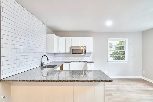 a kitchen with granite countertop a sink a stove and cabinets