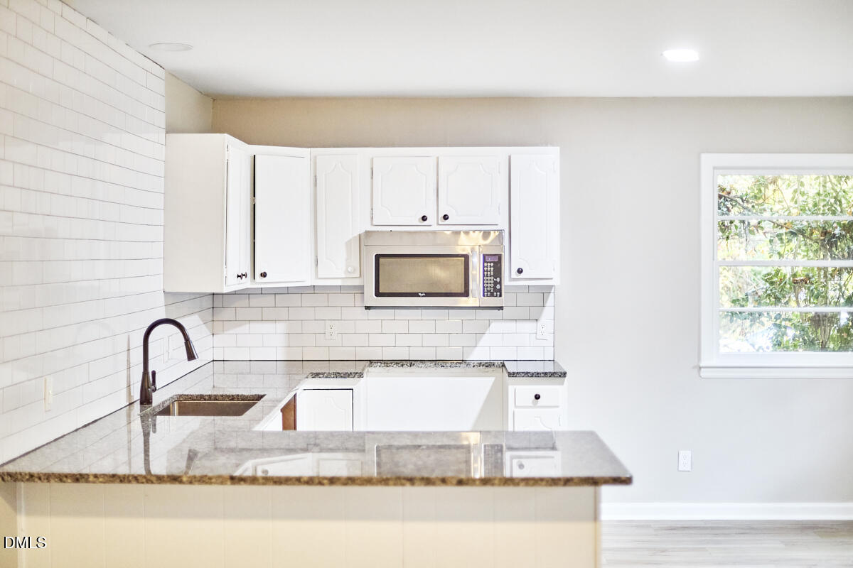 2128 Strebor Street Durham, NC 27705 - Photo 33 of 51 a kitchen with granite countertop a sink a stove and a microwave