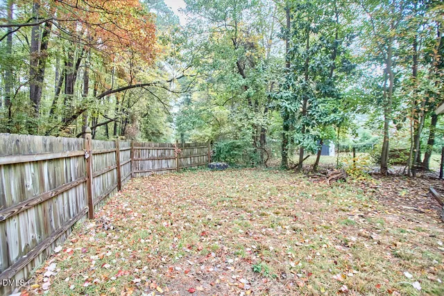 a view of backyard with wooden fence and large trees
