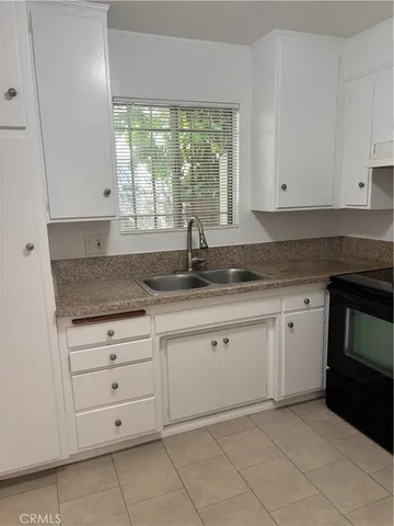 a kitchen with granite countertop white cabinets sink and dishwasher a stove with wooden floor
