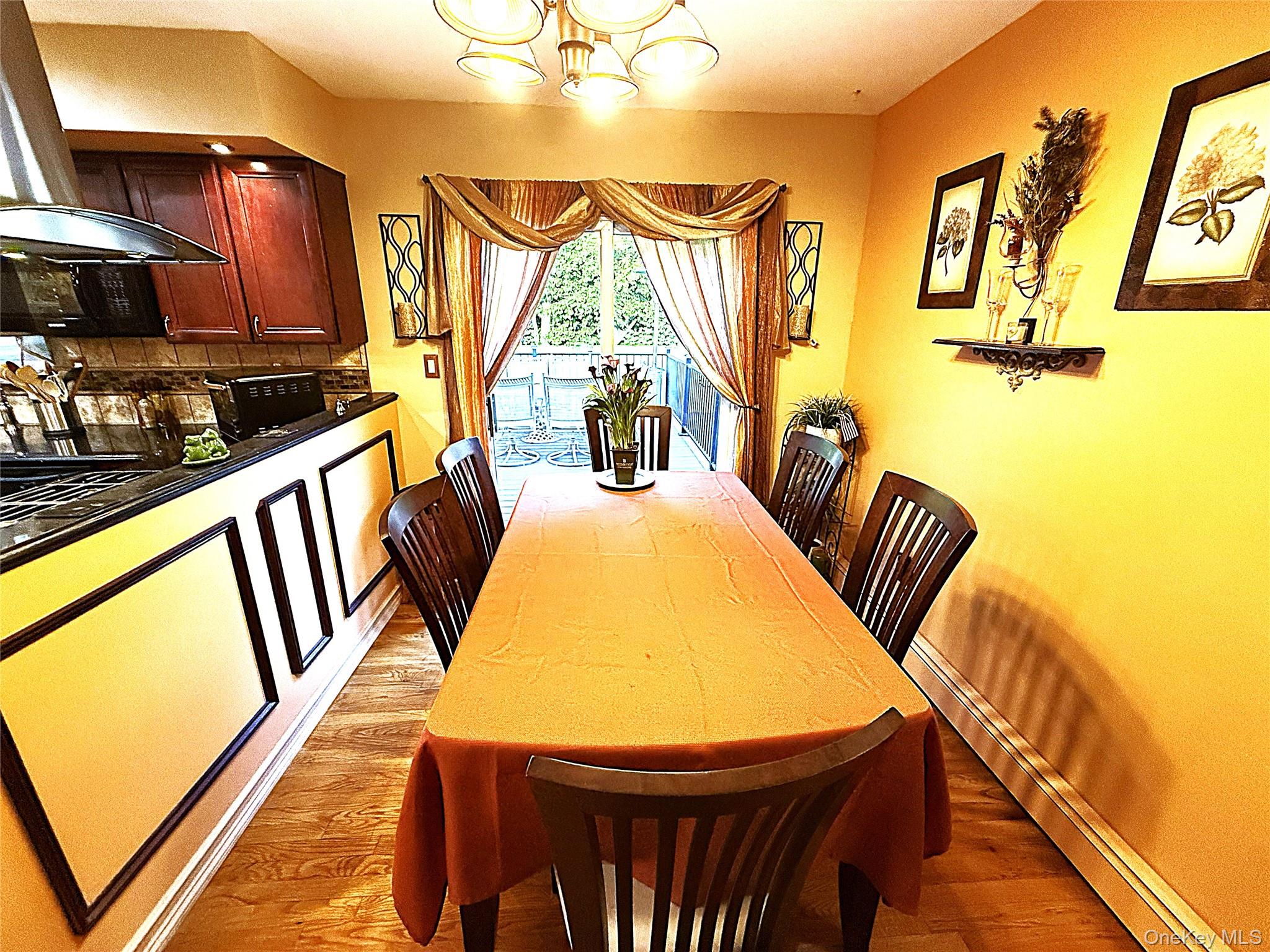1 Heston Road Shirley, NY 11967 - Photo 17 of 32 Dining area with wood-finish flooring, featuring a kitchen pass-through with dark cabinetry and a dark countertop