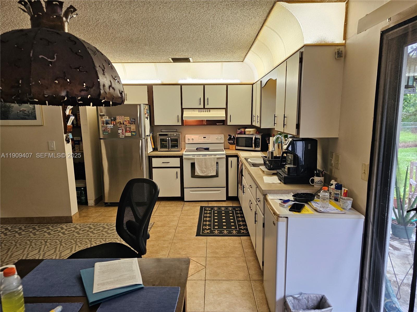 5108 Myrtle Drive Fort Pierce, FL 34982 - Photo 13 of 30 a kitchen with stainless steel appliances a stove a refrigerator a sink a counter space and a window