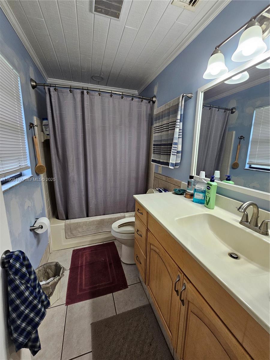 5108 Myrtle Drive Fort Pierce, FL 34982 - Photo 19 of 30 a bathroom with a sink a toilet a mirror and shower curtain