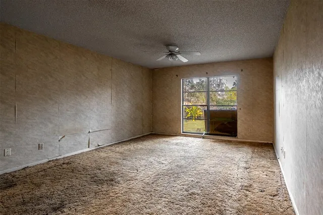 an empty room with chandelier fan and windows