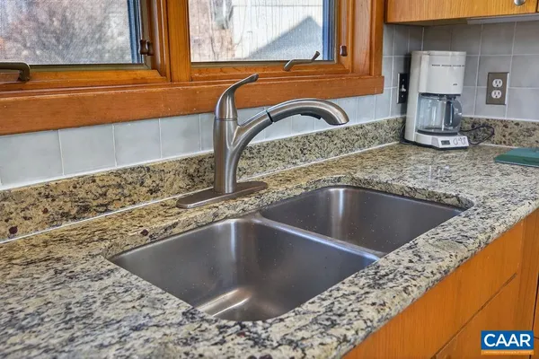 a kitchen with granite countertop a sink a counter top space appliances and cabinets