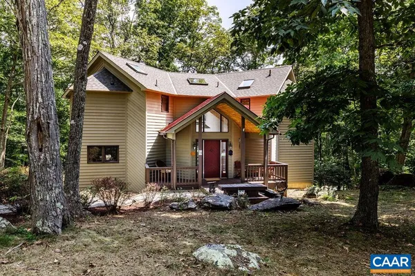 a view of a house with a yard and large trees