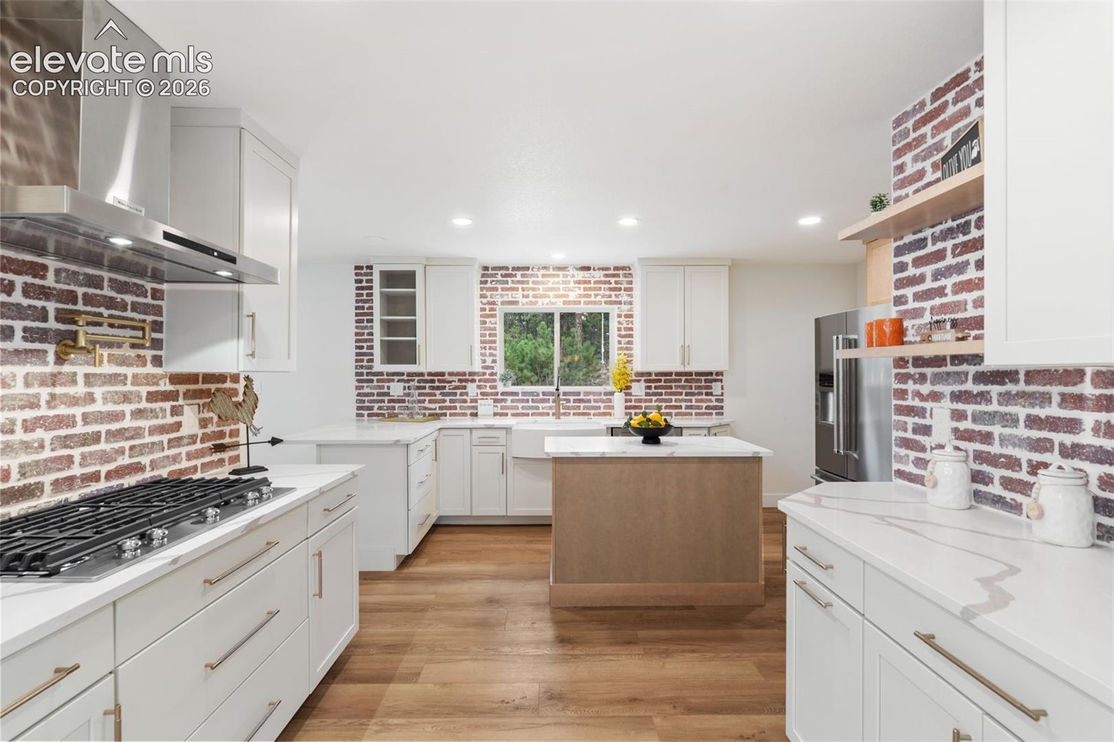 11665 Greentree Road Colorado Springs, CO 80908 - Photo 11 of 43 Kitchen featuring wall chimney exhaust hood, white cabinetry, appliances with stainless steel finishes, light wood-style flooring, and recessed lighting