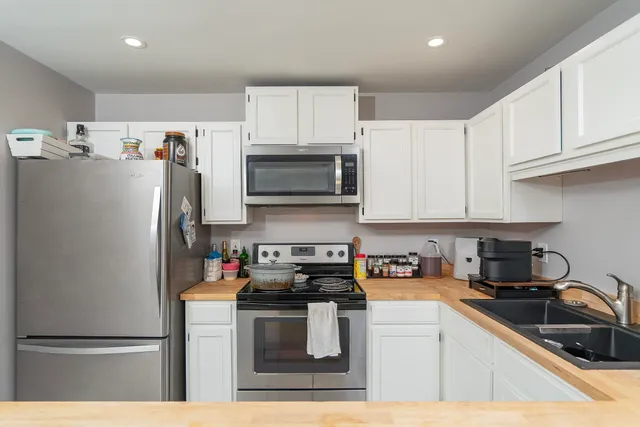 a kitchen with refrigerator a microwave a sink and cabinets