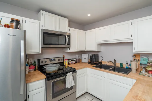 a kitchen with stainless steel appliances granite countertop white cabinets a stove a microwave and a refrigerator